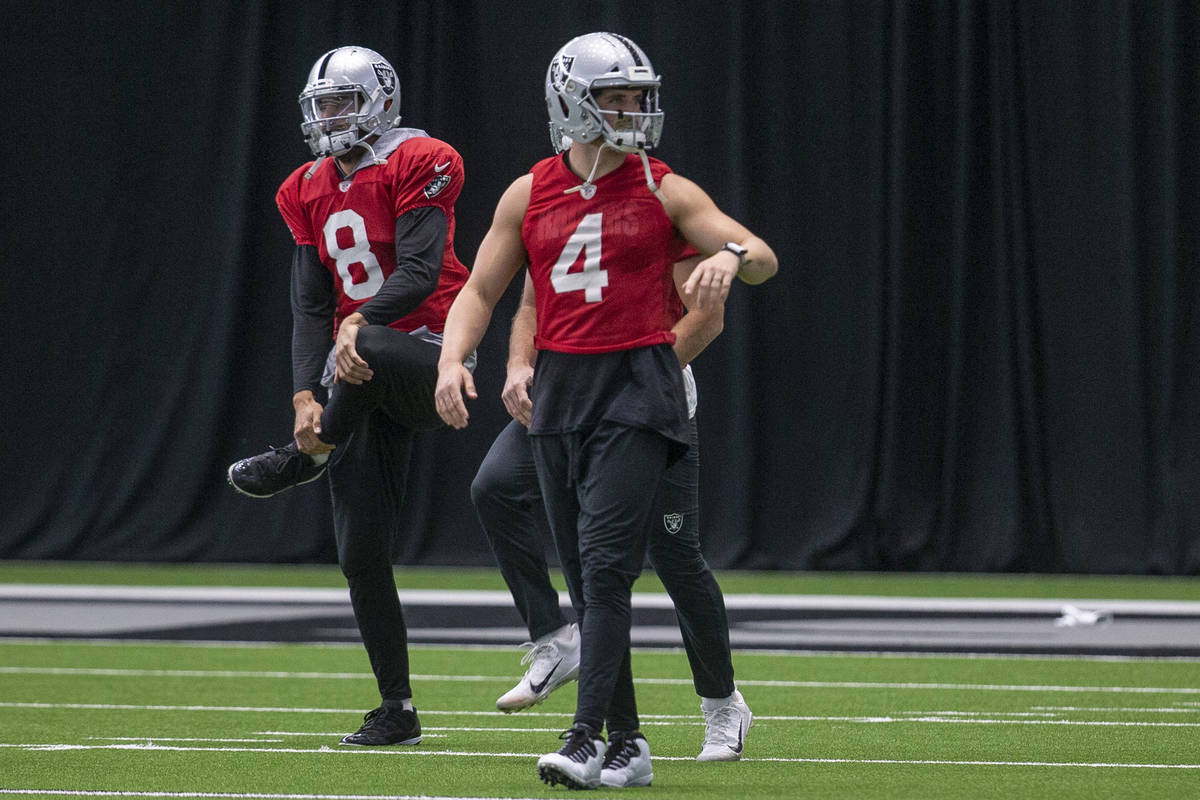 Las Vegas Raiders quarterbacks Marcus Mariota (8) and Derek Carr (4) stretch during a practice ...