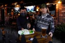 A waiter serves food to a customer at Ye Olde King's Head on Thursday, Nov. 19, 2020, in Santa ...