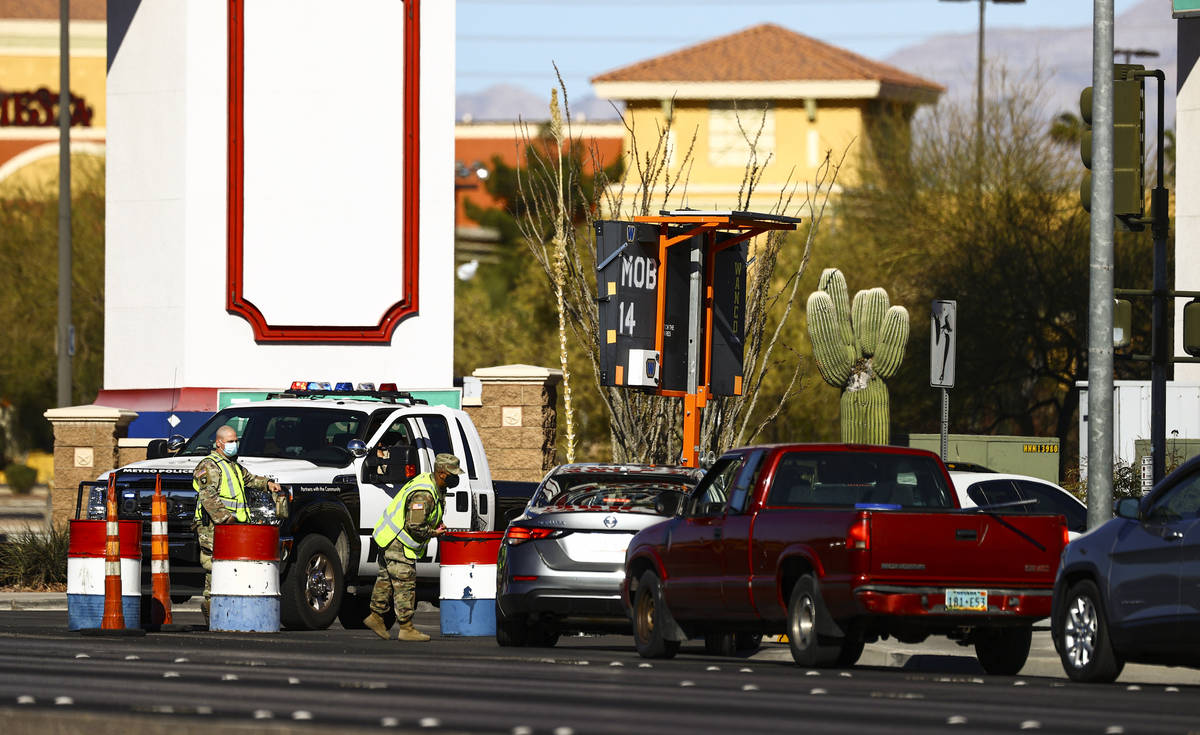 Members of the National Guard assist as people wait in line at the drive-thru COVID-19 testing ...