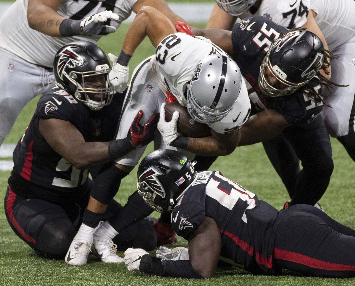 Las Vegas Raiders running back Devontae Booker (23) is gang tackled by Atlanta Falcons defensiv ...