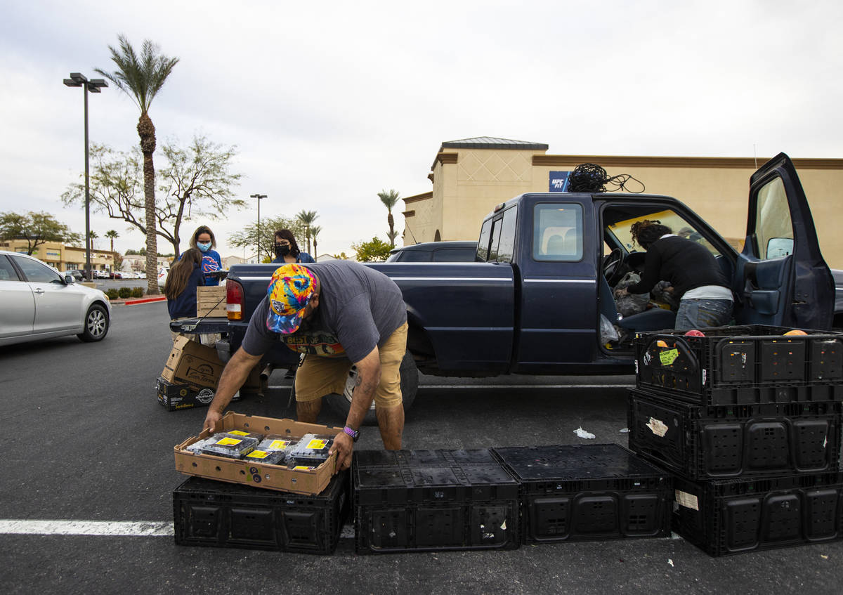Zach Lopez, left, assists Amber Stevenson in giving out food at a shopping center in Las Vegas ...