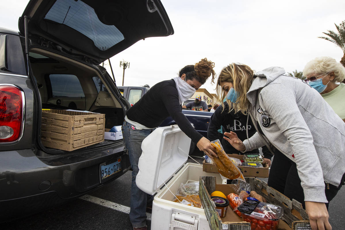 Amber Stevenson, left, hands out food to people in need at a shopping center in Las Vegas on We ...