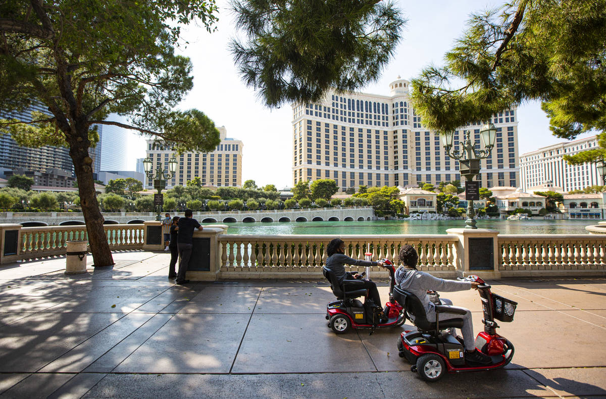 People pass by the Bellagio fountains while riding mobility scooters on the Las Vegas Strip on ...