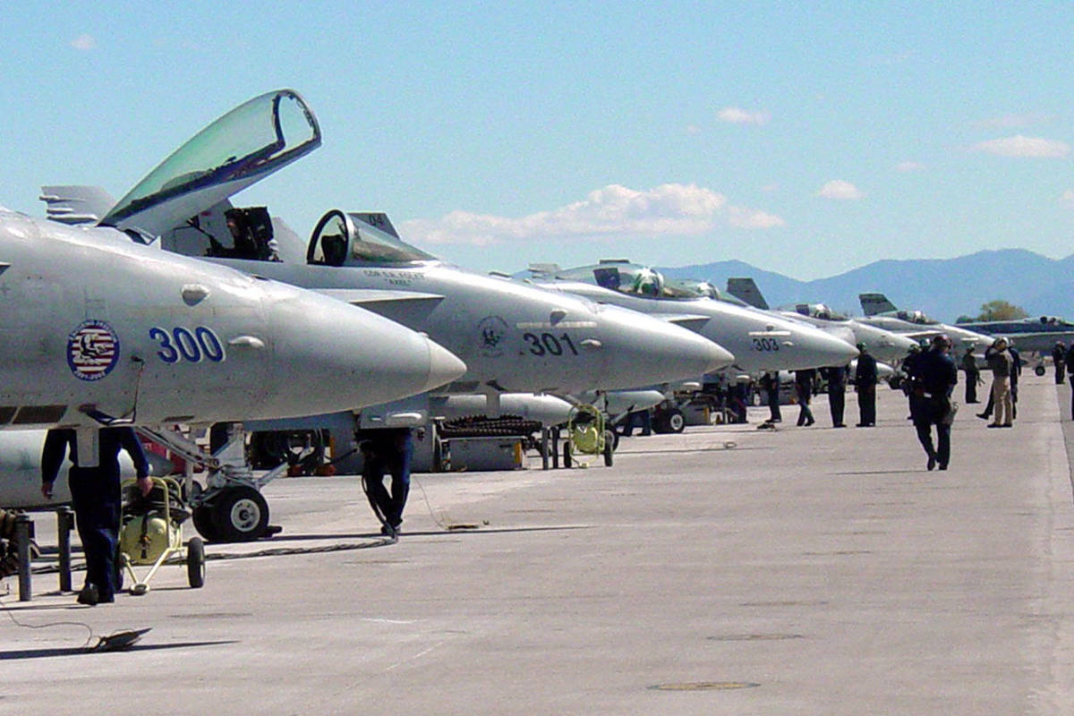 Maintenance personnel move along the flightline of F/A-18 Hornet Strike Fighter aircraft attach ...