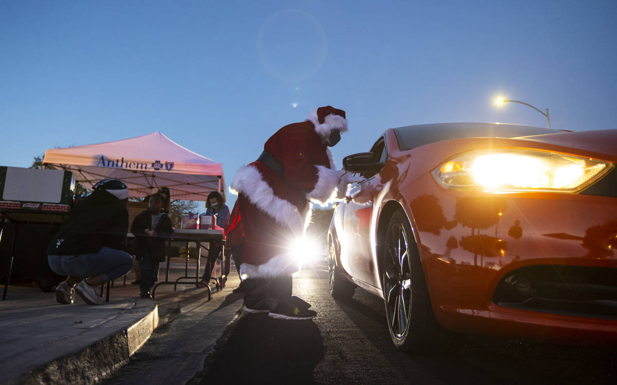 A retired Metro police captain hands out treats as part of a charity drive-thru event for famil ...