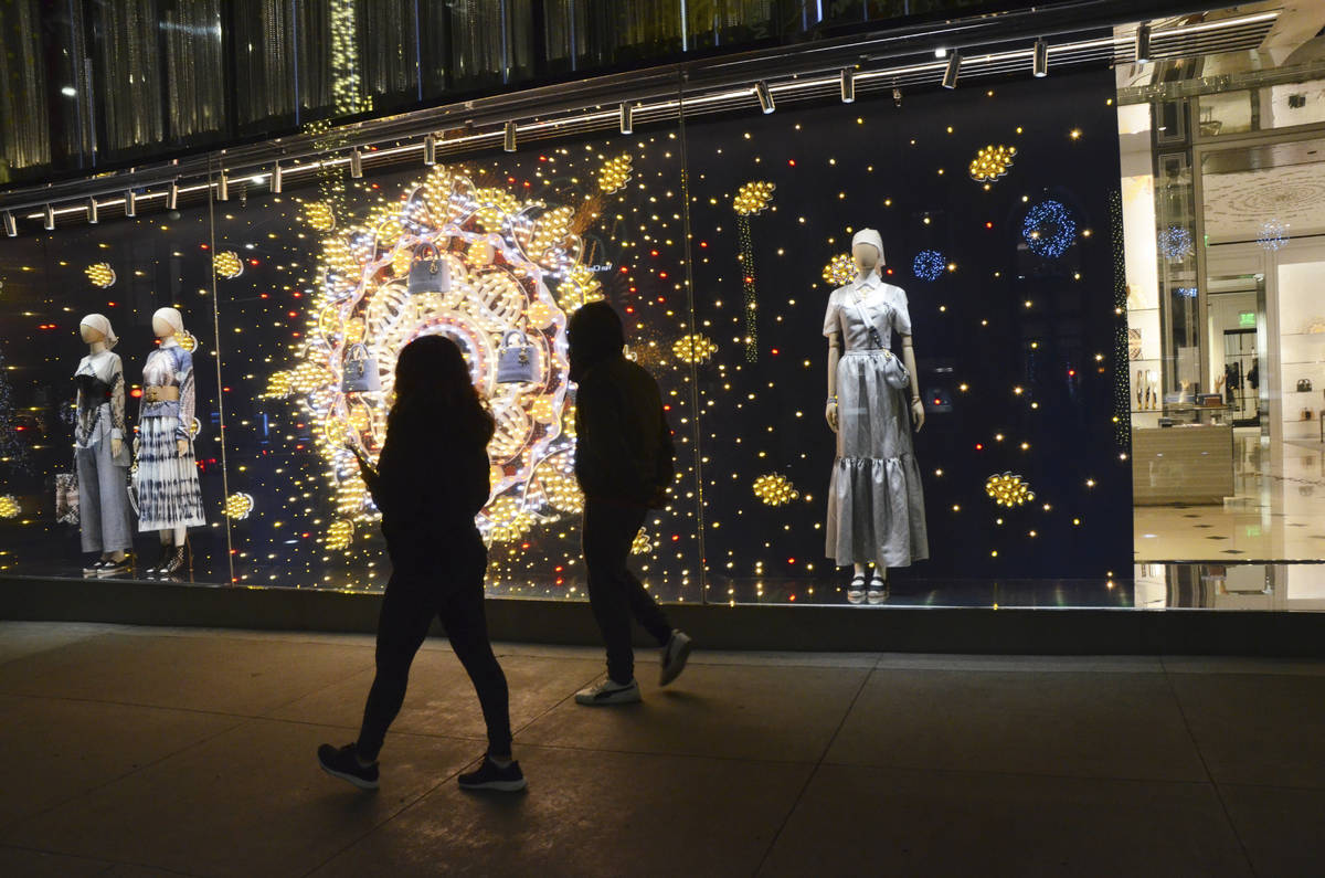 Two people walk past the holiday window display at the Dior store