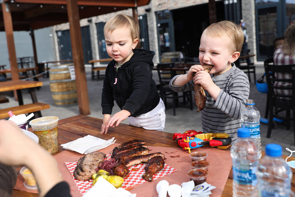 Mason Hall, 2, left, joins her brother Kingsley Hall, 4, right, as he eats at the SoulBelly BBQ ...