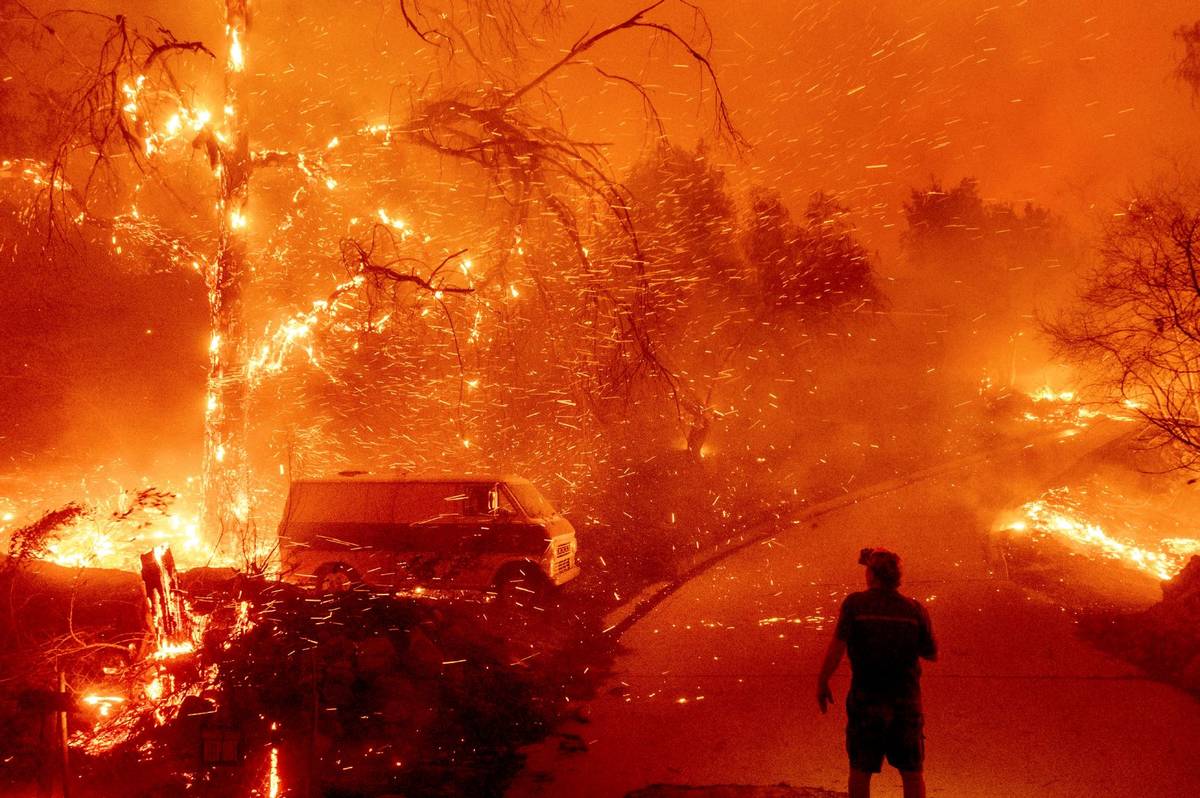 Bruce McDougal watches embers fly over his property as the Bond Fire burns through the Silverad ...
