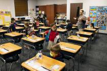 Susan Villagracia, kindergarten teacher, directs her student where to sit during the first day ...