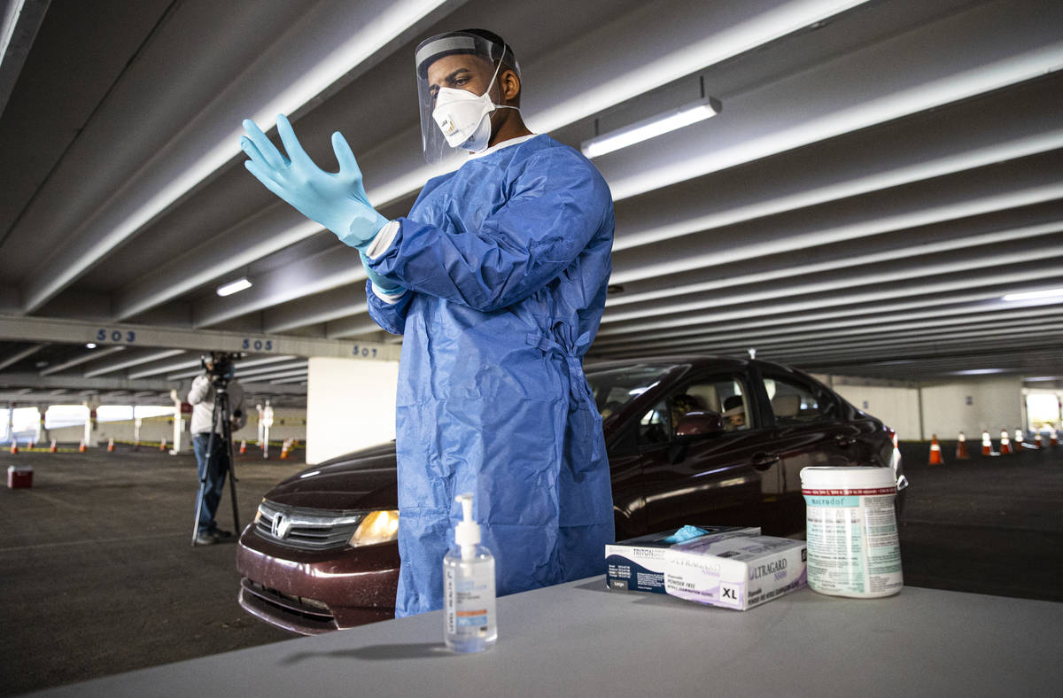 Nevada National Guard Spc. Demetrie Barnett puts on a fresh pair of gloves before taking a swab ...