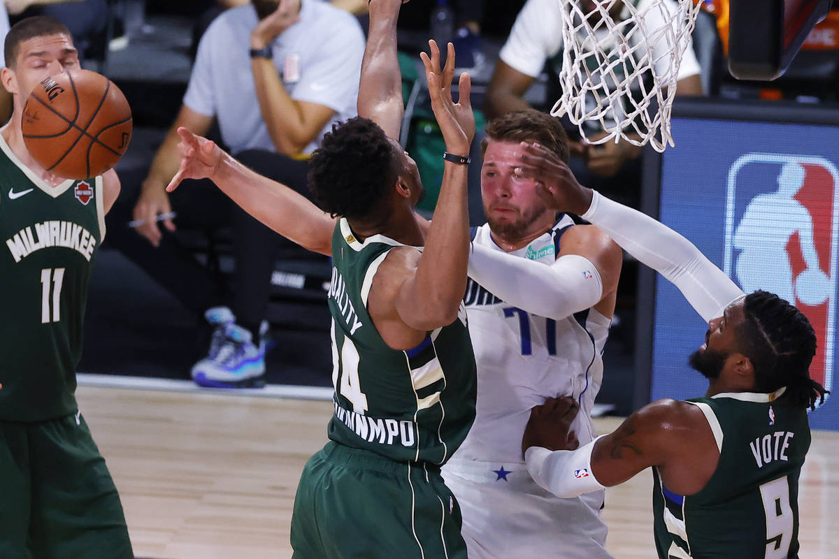 Dallas Mavericks' Luka Doncic passes away from Milwaukee Bucks' Giannis Antetokounmpo (34) and ...