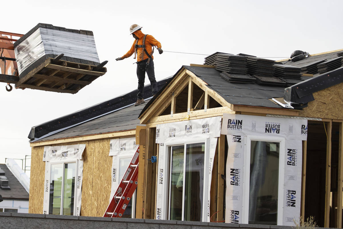 Construction workers unload roofing materials at Moderne at Centennial construction site where ...