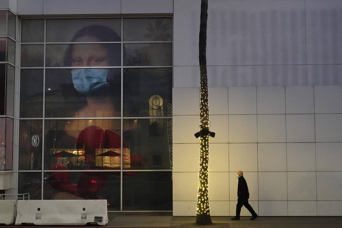A masked pedestrian walks past of a COVID 19-themed mural depicting Leonardo da Vinci's Mona Li ...