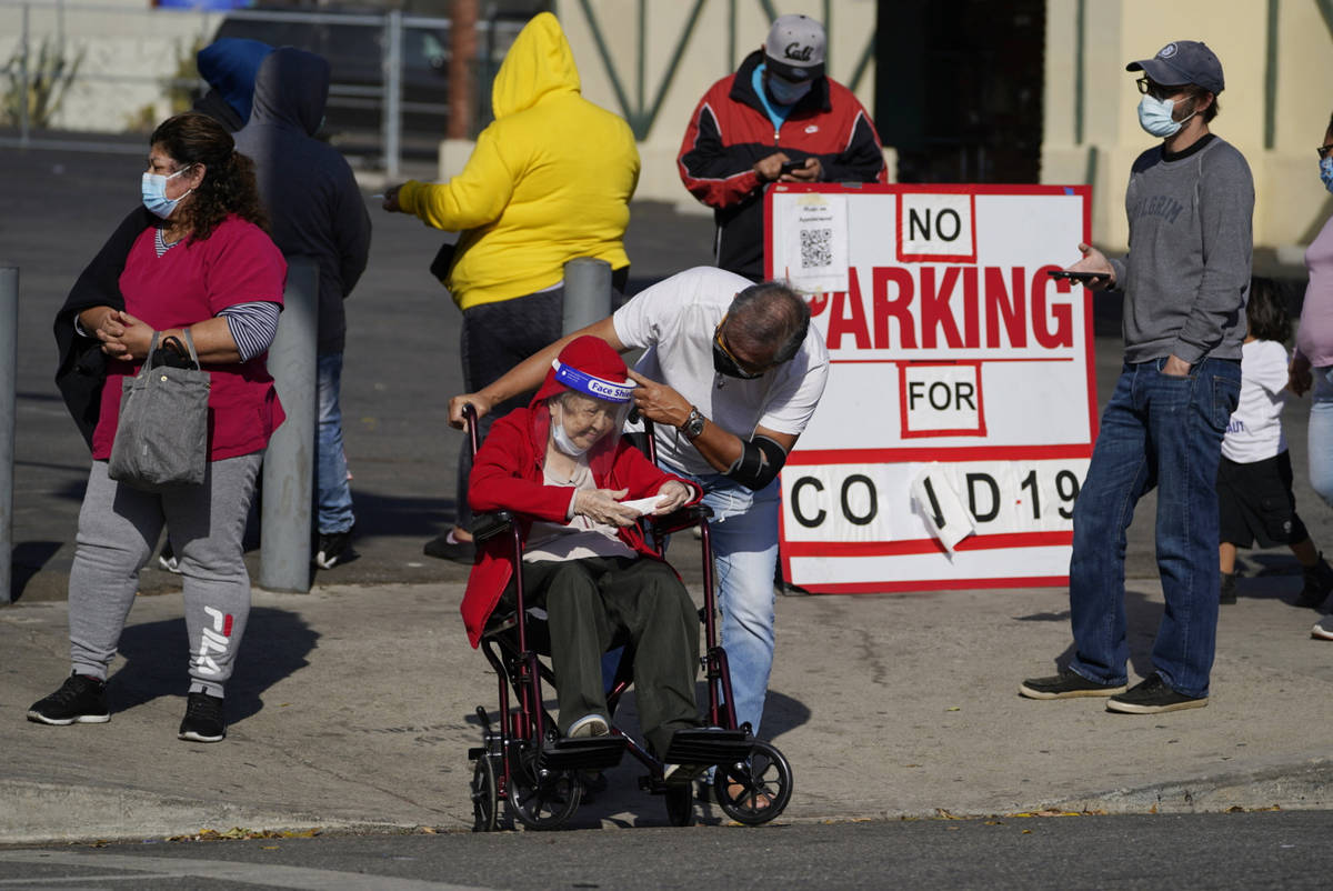 People wait in line on the sidewalk for a free COVID-19 test outside the Echo Park branch of th ...
