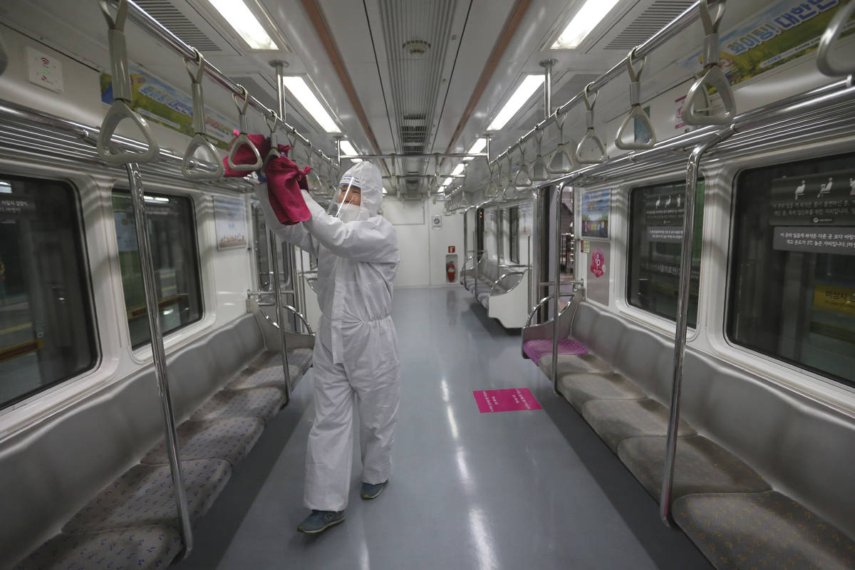 An employee disinfects handles as a precaution against the coronavirus on a subway train at a s ...
