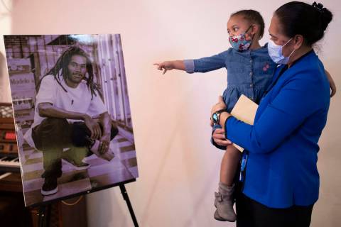 June Atkins, right, mother of Genesis Atkins, holds Tiye Egypt, 2, as she points at a photo of ...