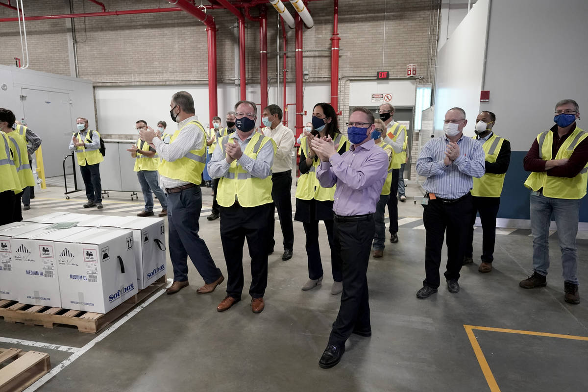 Pfizer employees clap after line workers finished packing boxes containing the Pfizer-BioNTech ...