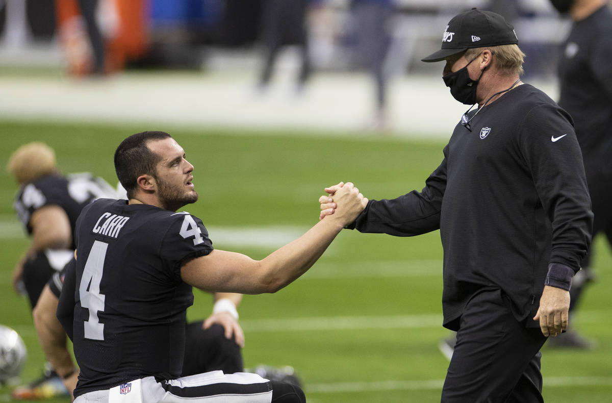 Raiders head coach Jon Gruden, right, greets Raiders quarterback Derek Carr (4) during warm ups ...