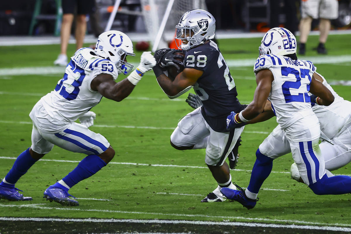 Raiders running back Josh Jacobs (28) tries to get past Indianapolis Colts defense, including o ...