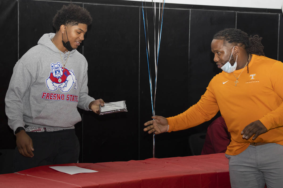 Desert Pines high school running back Malik Brooks, singing with Fresno State, left, receives a ...