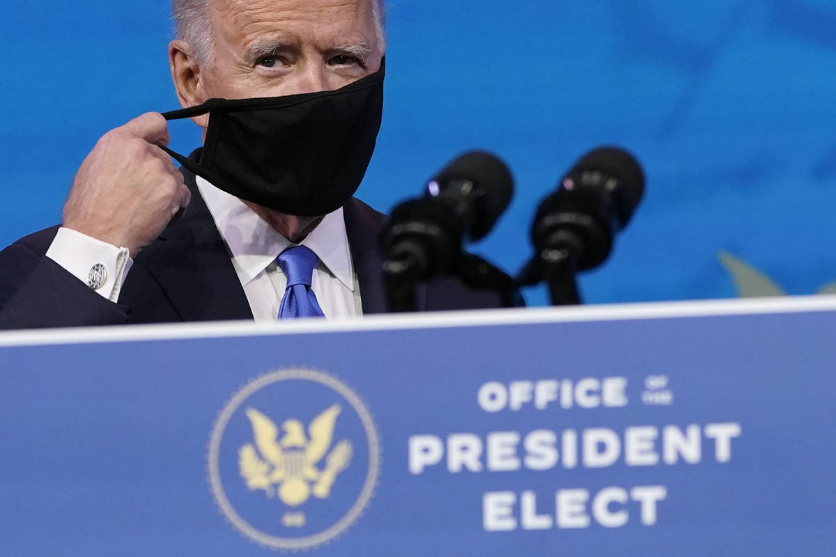 President-elect Joe Biden removes his mask as he arrives to speak after the Electoral College f ...