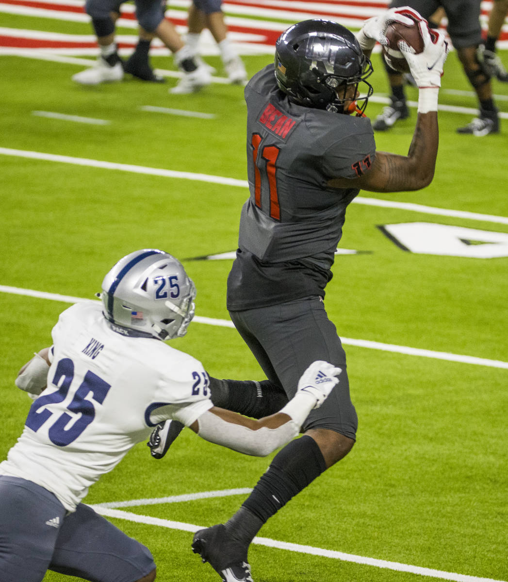 UNLV Rebels tight end Noah Bean (11, top) secures a pass above Nevada Wolf Pack defensive back ...