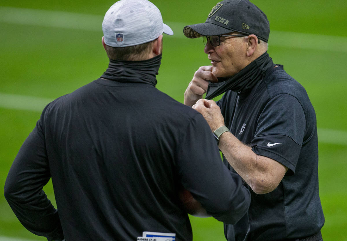 Raiders defensive line coach Rod Marinelli, right, adjusts his face mask before an NFL football ...