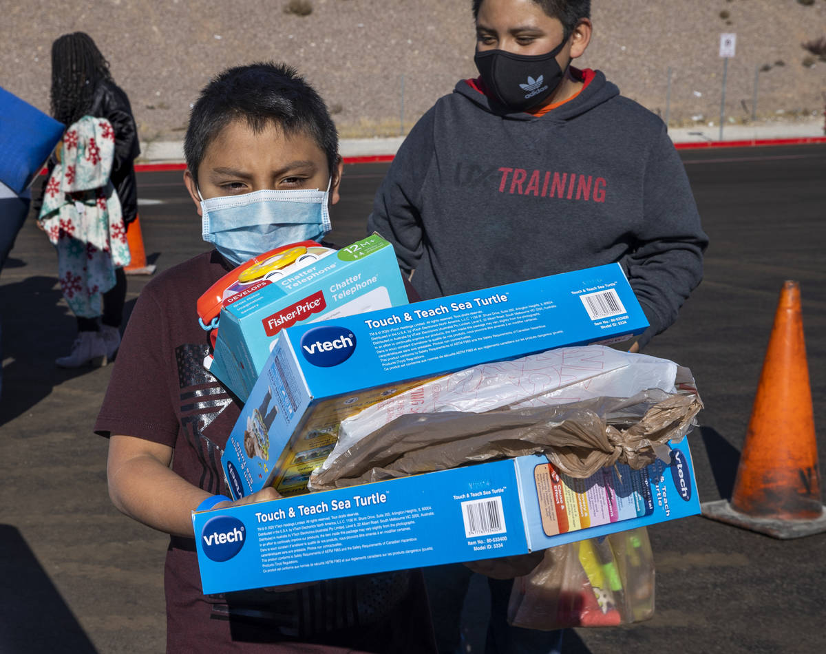 Miguel Geronimo, 8, is loaded with gifts received during the Las Vegas Rescue Mission toy drive ...