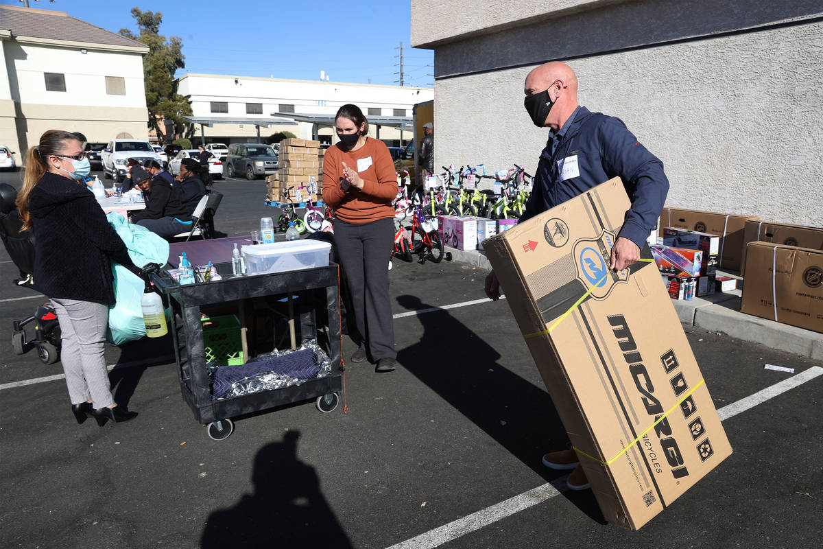 Volunteer Brian McMains, right, delivers a boxed bicycle to a client's vehicle during HELP of S ...