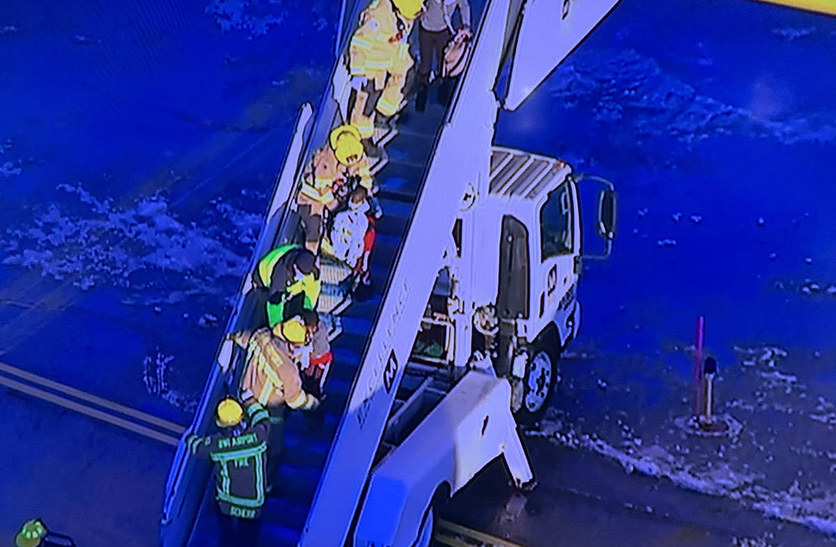 Passengers from Spirit Flight 696 are helped down the ramp after the plane from Las Vegas skidd ...