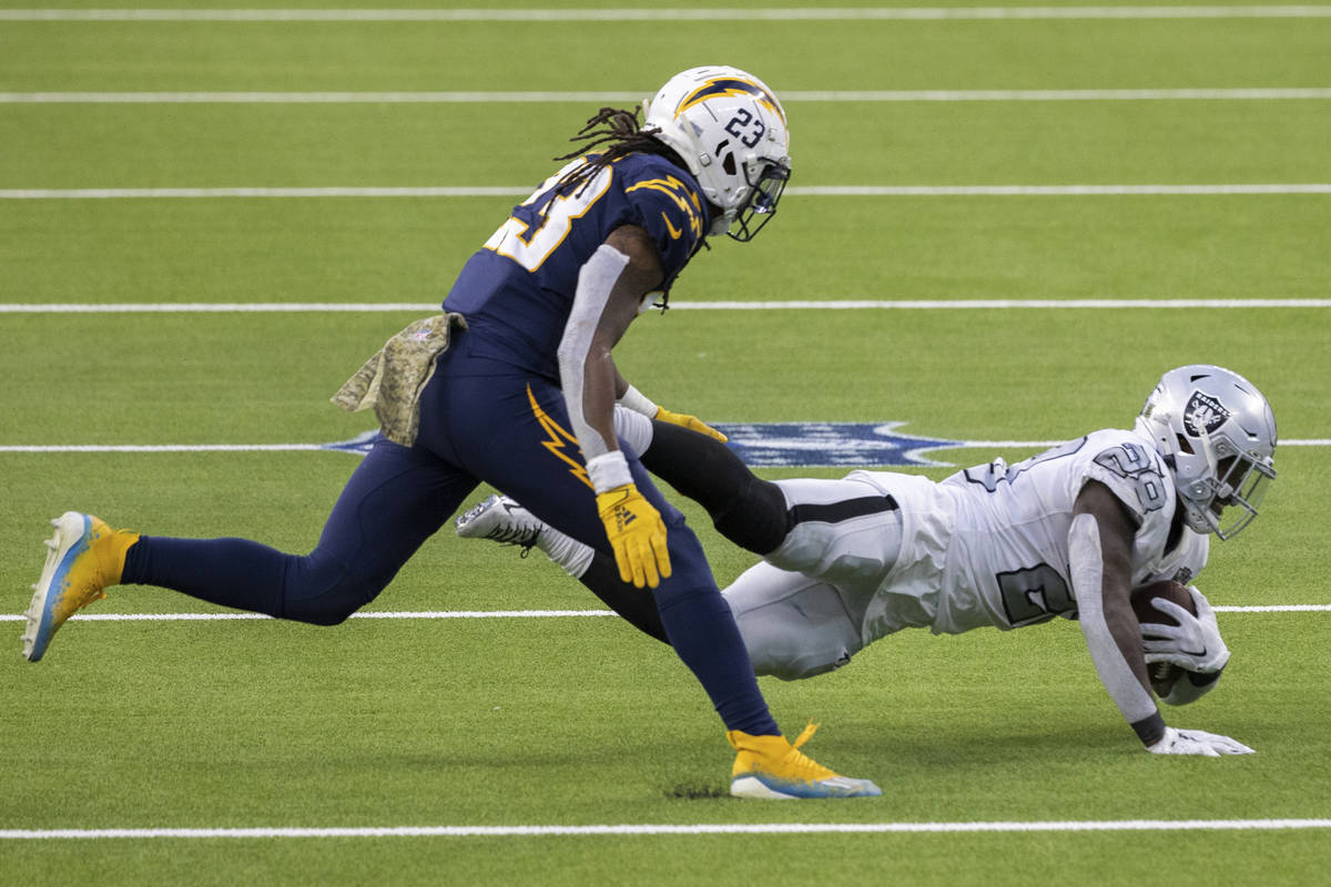 Las Vegas Raiders running back Josh Jacobs (28) leaps forward for extra yardage past Los Angele ...