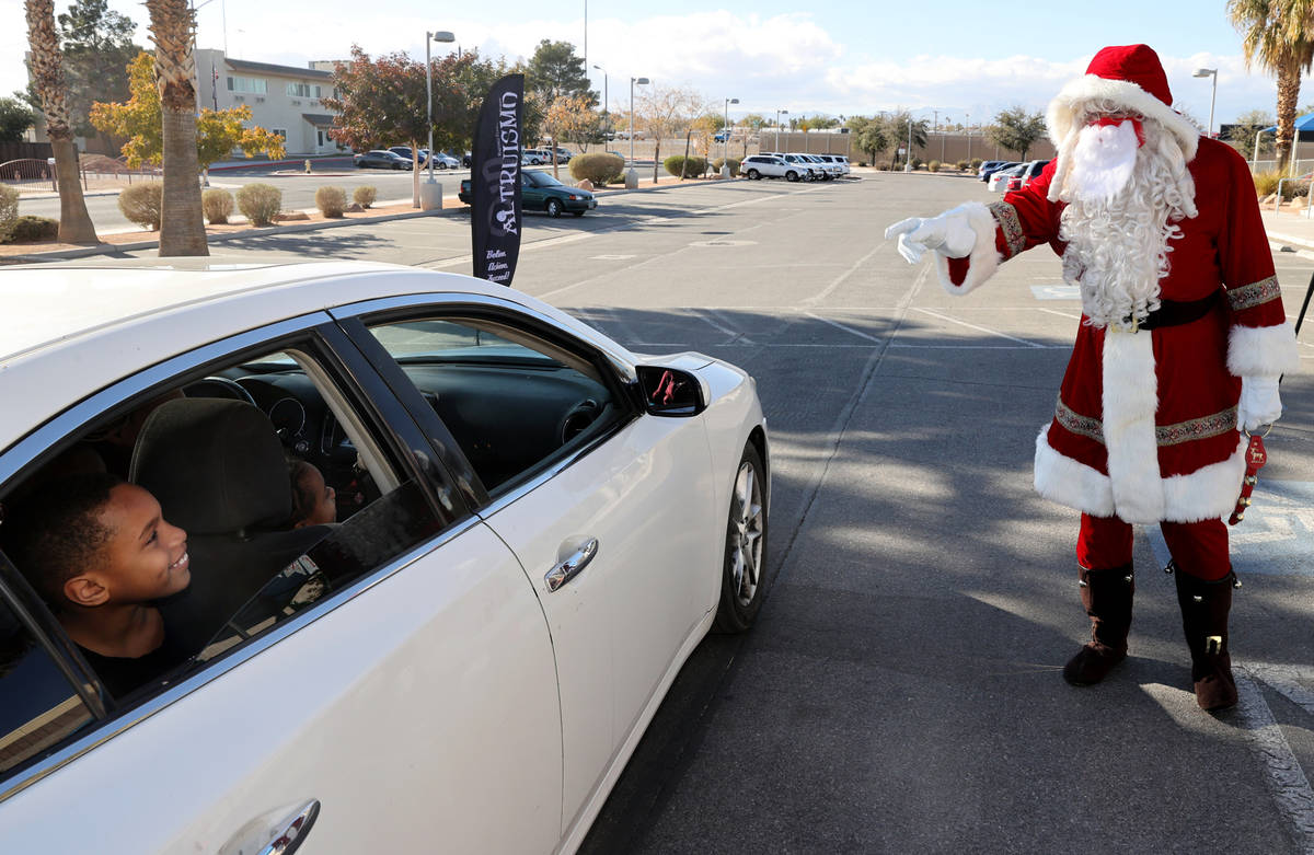 Kayden Bush, 8, greets Santa during a drive-thru gift giveaway at Martinez Elementary School in ...
