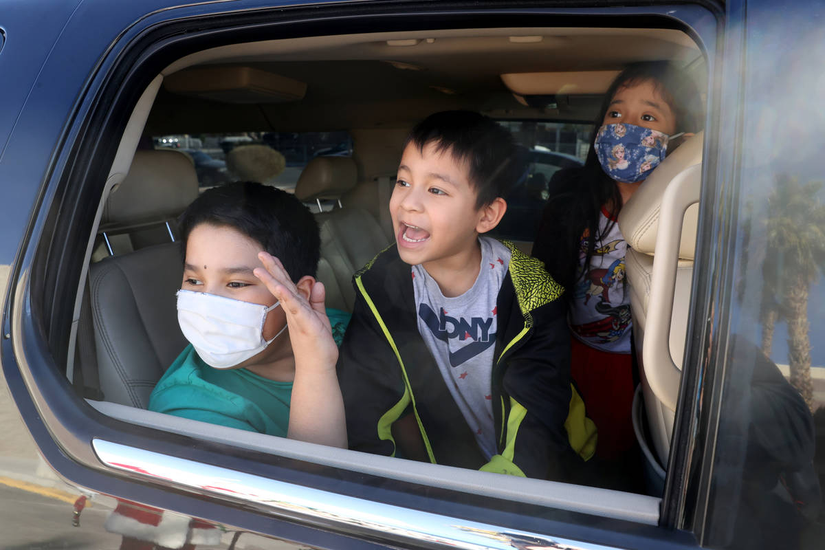 Siblings, from left, Angel, 9, Jose, 5, and Natalie, 7, see Santa during a drive-thru gift give ...