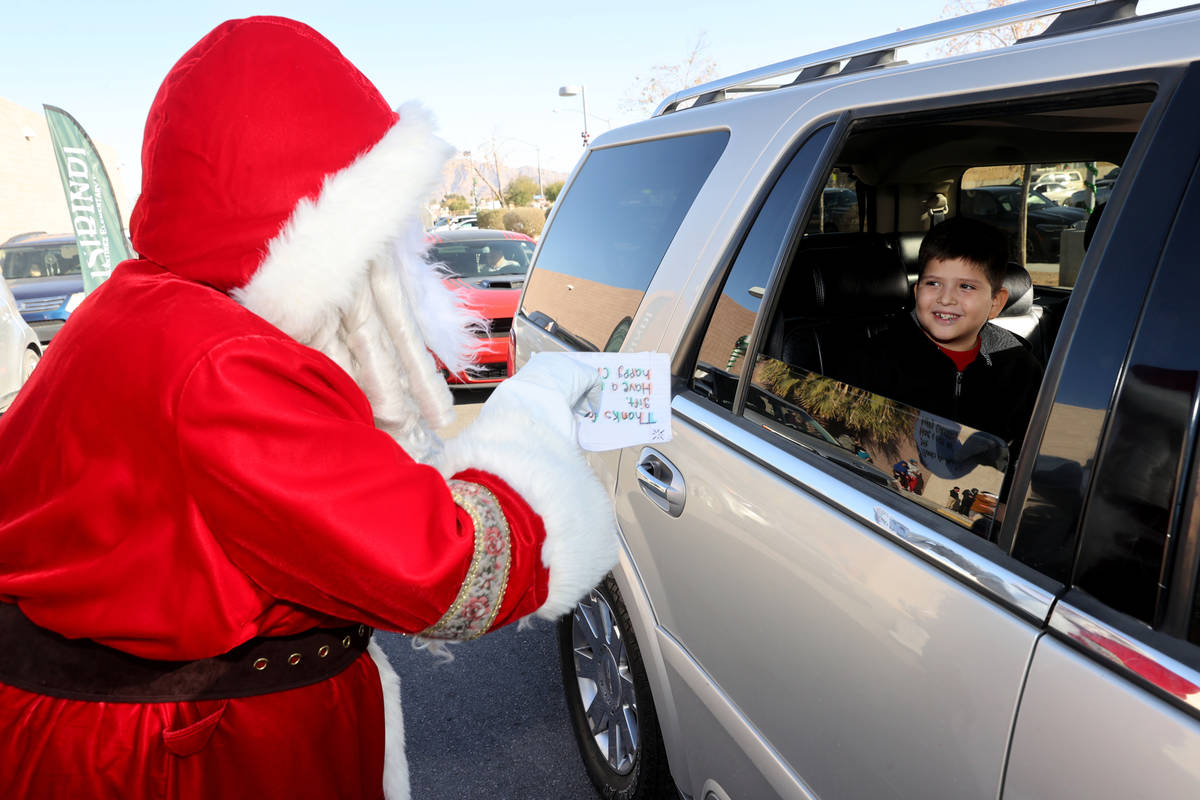 Kayden Bush, 8, greets Santa during a drive-thru gift giveaway at Martinez Elementary School in ...