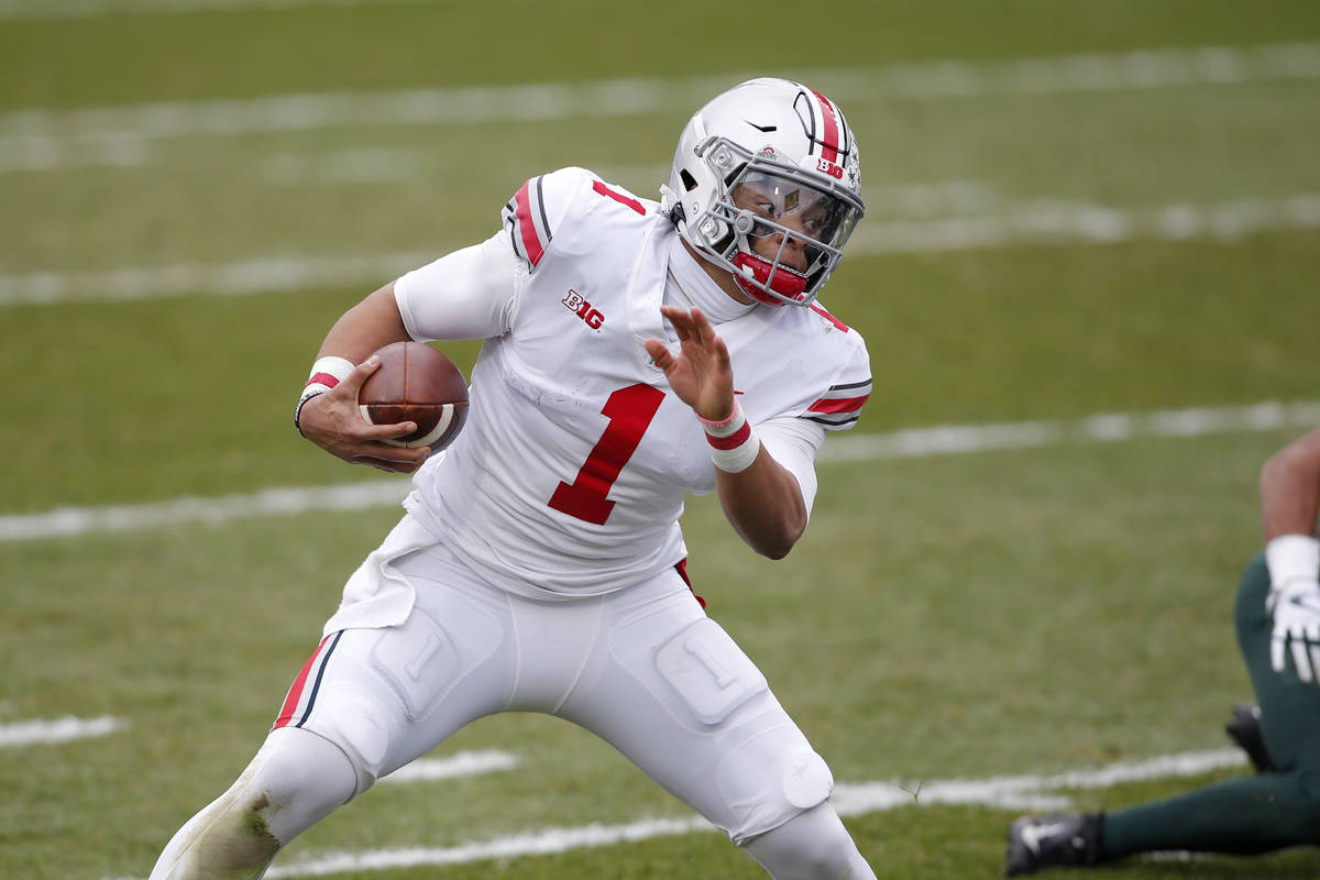 Ohio State quarterback Justin Fields scrambles against Michigan State during an NCAA college fo ...