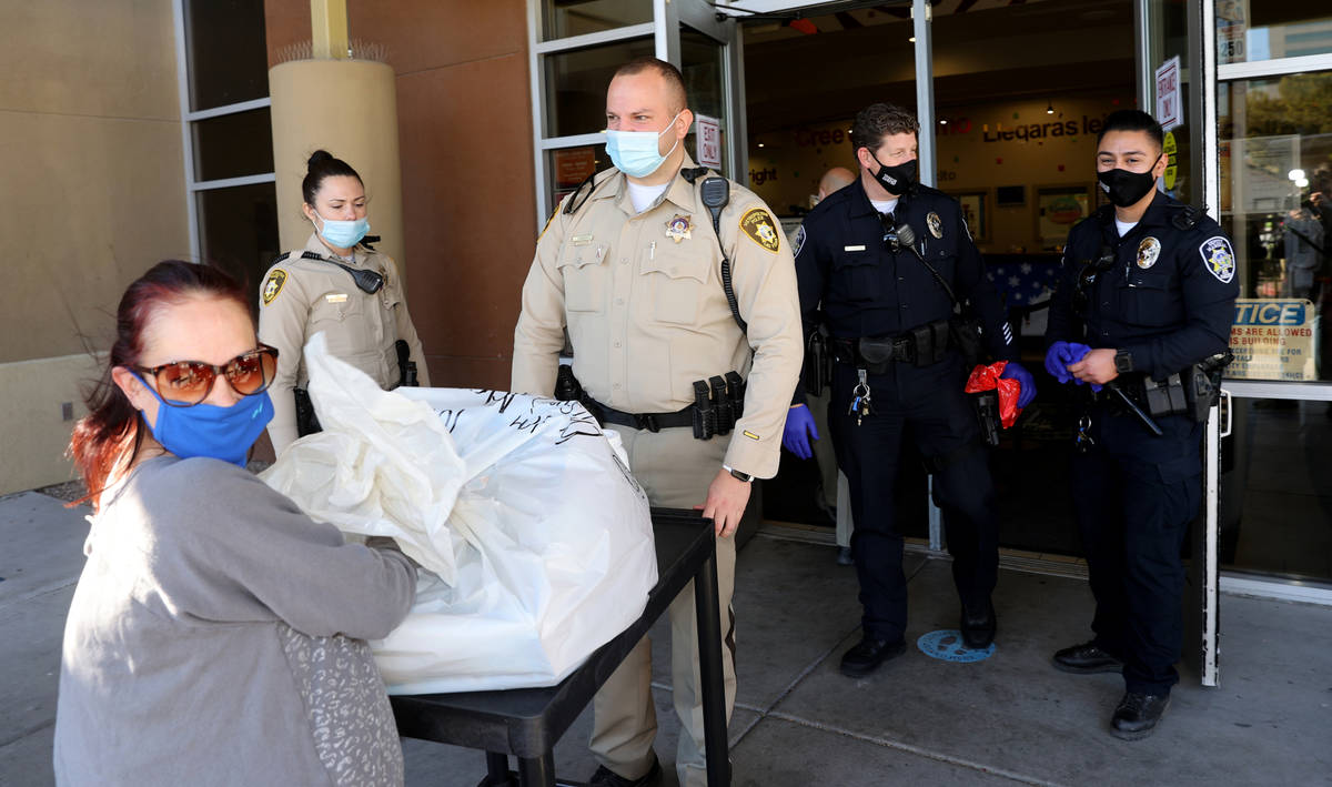 Las Vegas police officer Adam Stankiewicz, center, loads toys and food for Christina Rivera, le ...