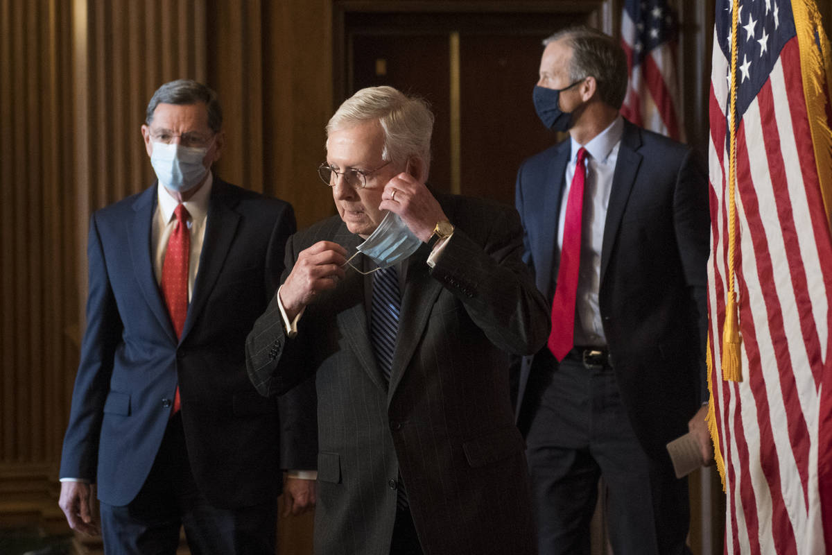 Senate Majority Leader Mitch McConnell of Ky., removes his face mask as he arrives with Sen. Jo ...