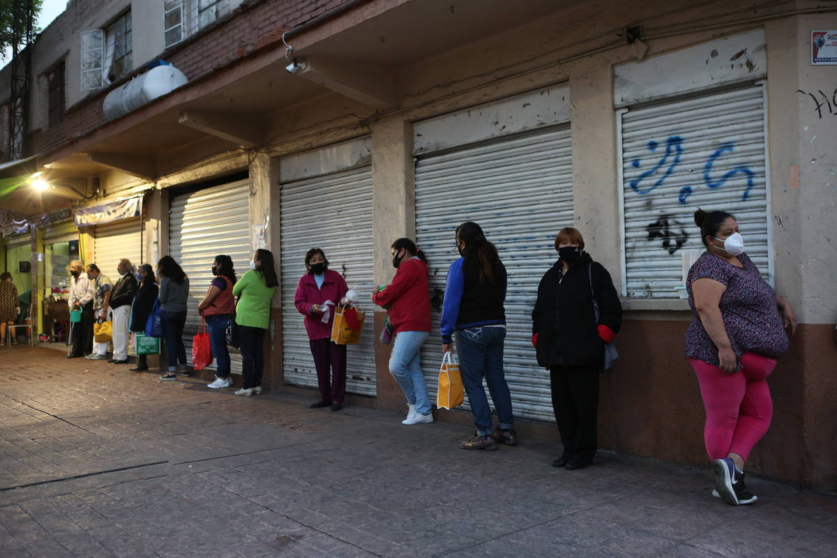 People line up for a free dinner at a soup kitchen in Mexico City, Saturday, Dec. 19, 2020, ami ...