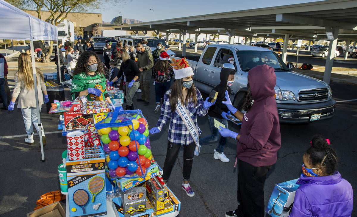 Volunteers hurry about delivering gifts during the first NLVPD Holiday Toy Giveaway drive-thru ...