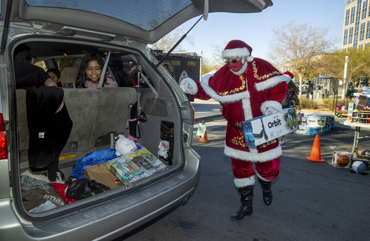 Santa Claus loads up gifts during the first NLVPD Holiday Toy Giveaway drive-thru event in the ...