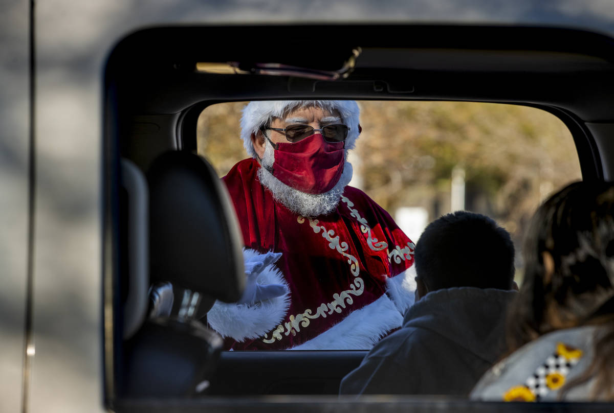 Santa Claus greets passengers during the first NLVPD Holiday Toy Giveaway drive-thru event in t ...