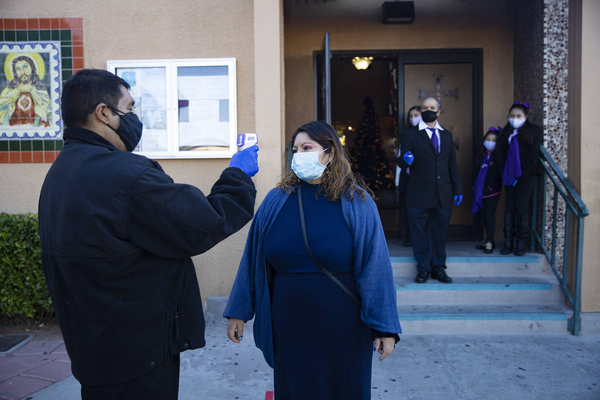 Apolinar Montoya takes the temperature of Teresa Valentine outside St. Anne's Catholic Church i ...