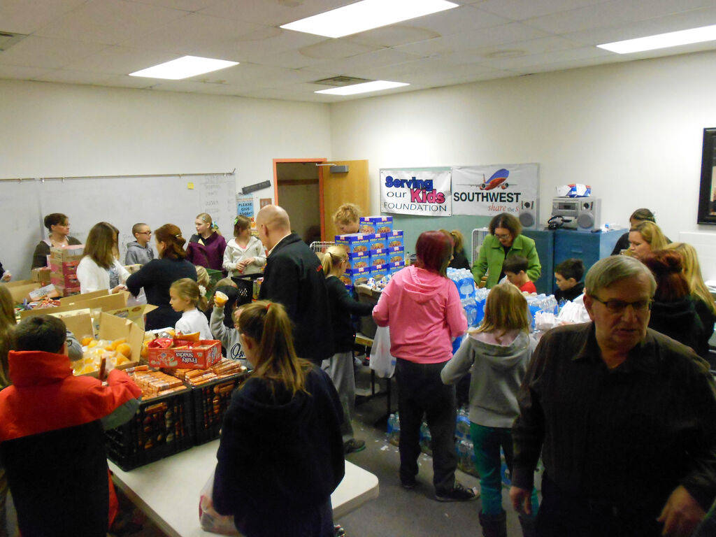 Volunteers fill food bags at the Serving Our Kids Foundation warehouse. (Linda J. Simpson) L ...