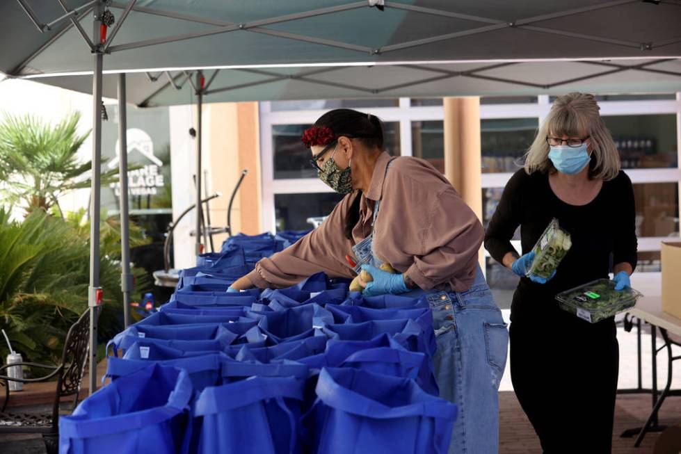 Volunteers Carrie Smith, left, and Shannon Oleson prepare bags for a food distribution at SHARE ...