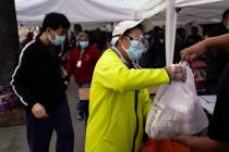 A woman receives a bag of groceries at a food bank at the Los Angeles Boys & Girls Club in ...