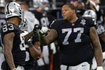 Raiders offensive tackle Trent Brown (77) fist bumps Raiders tight end Darren Waller (83) in th ...