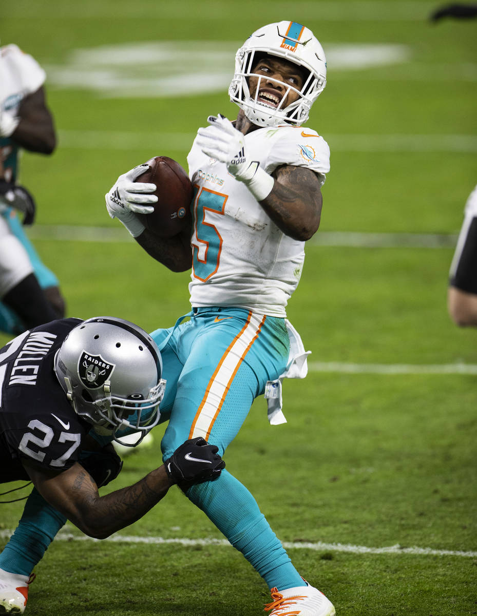 Raiders cornerback Trayvon Mullen (27) tackles Miami Dolphins running back Lynn Bowden (15) dur ...