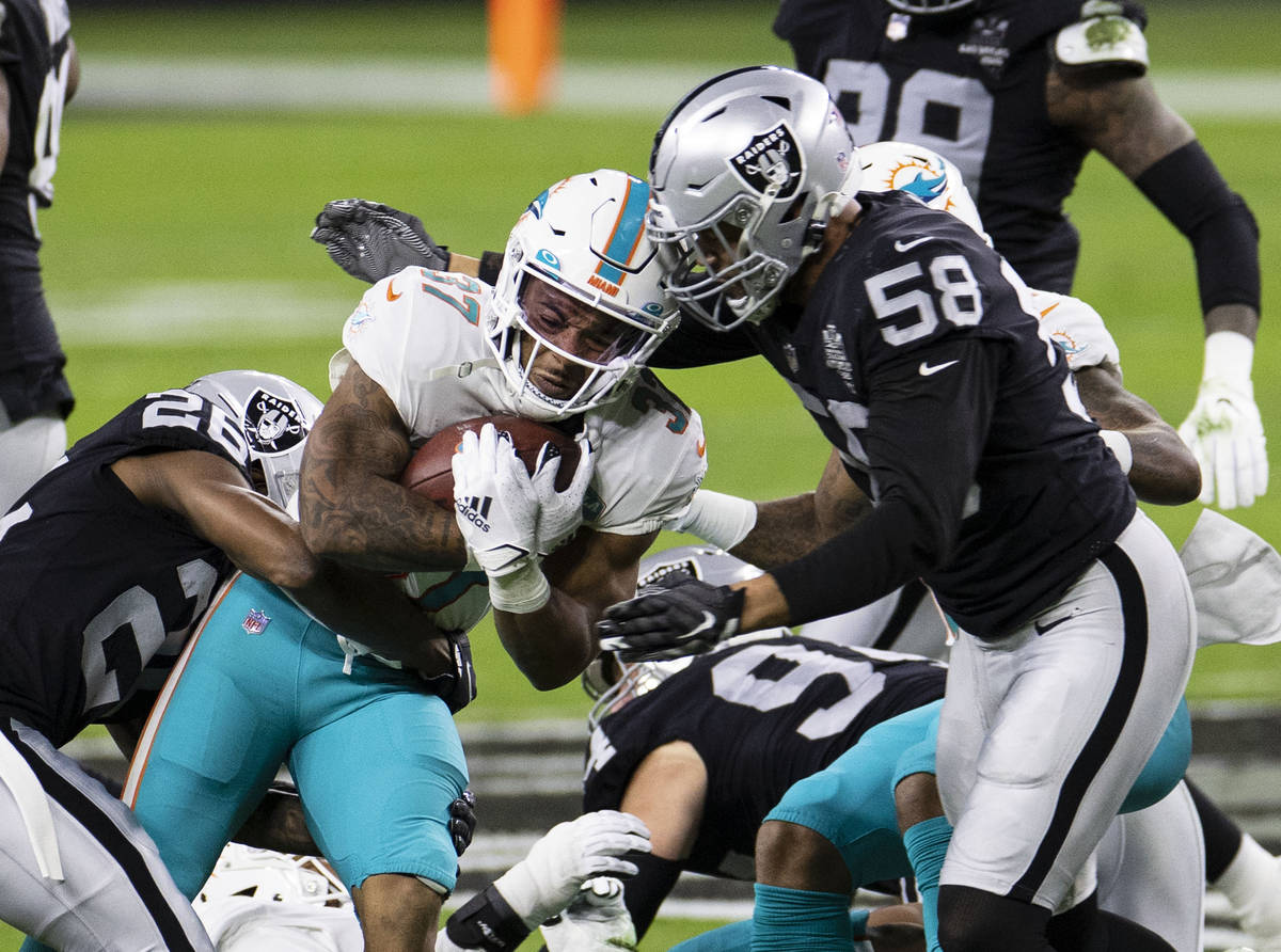 Raiders cornerback Nevin Lawson (26) and linebacker Kyle Wilber (58) defend Miami Dolphins runn ...