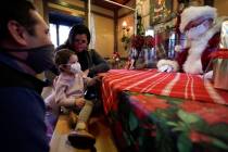 Kenny Souza, left, Sophia Souza, 2, and Nashua Souza wear face masks while talking with Ray Ham ...