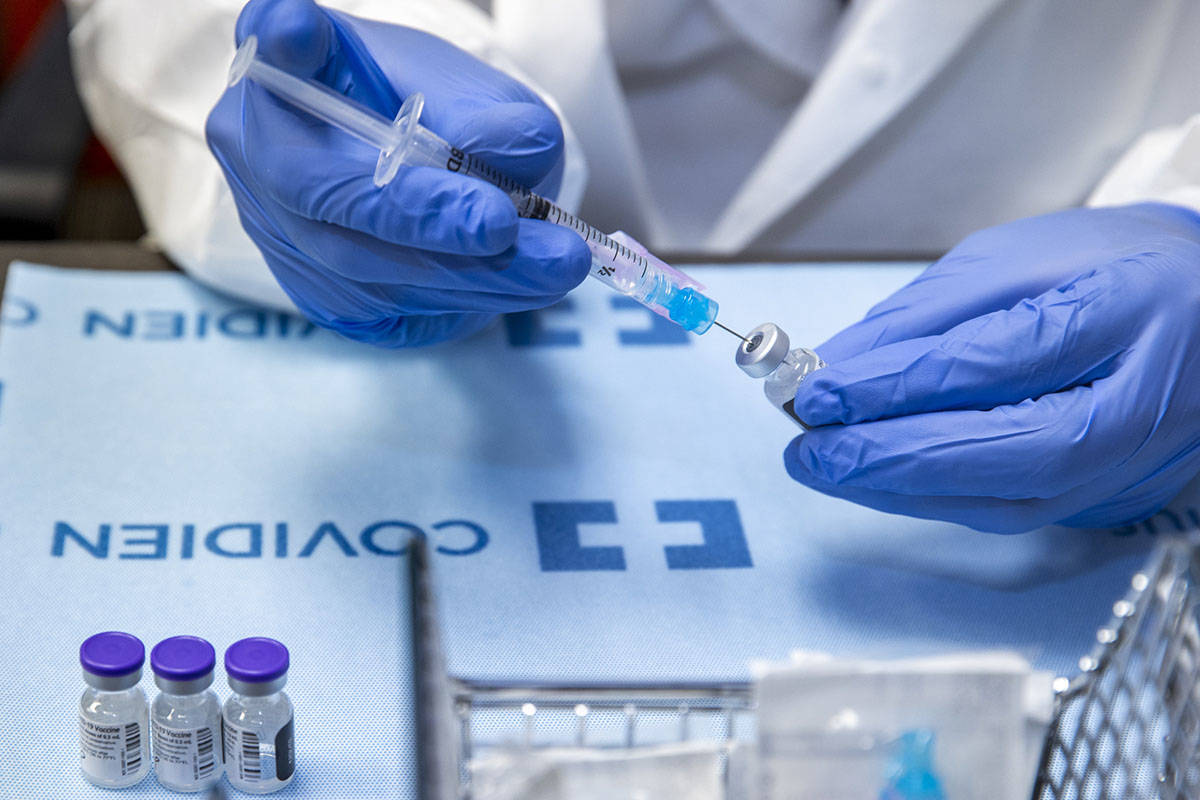 Student pharmacist Wilbur Quimba loads up new syringes with vaccine as University Medical Cente ...